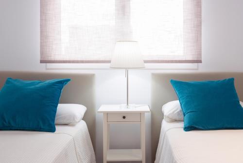 1 dormitorio con 2 camas, almohadas azules y lámpara en Hercot Canteras Beach,Sun,City WIFI free, en Las Palmas de Gran Canaria