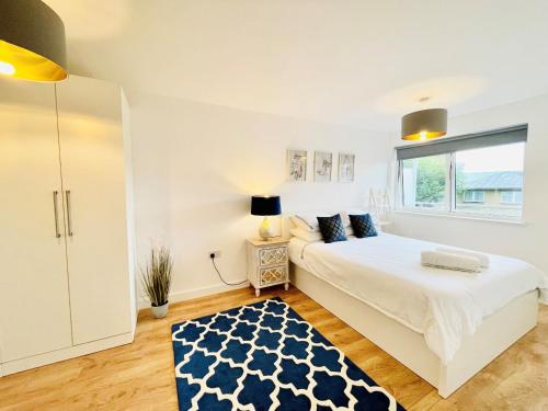a white bedroom with a bed and a window at Hamptons Point in Enfield