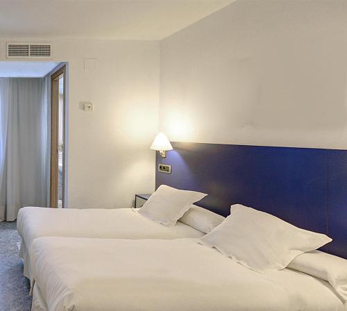 two beds in a hotel room with white pillows at Hotel Vila-real Azul in Villareal