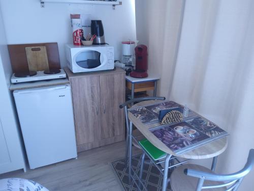 una pequeña cocina con mesa y microondas en Chambre d'hôtes en Lunel