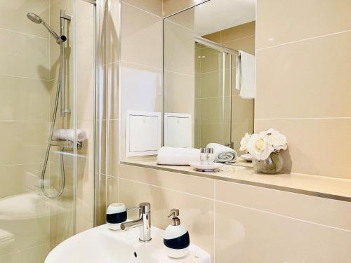 a bathroom with a sink and a shower and a mirror at Hamptons Point in Enfield