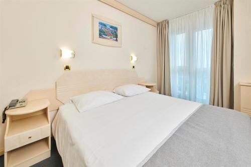 a bedroom with a large white bed and a window at Hotel Gran Vista Plava Laguna in Poreč