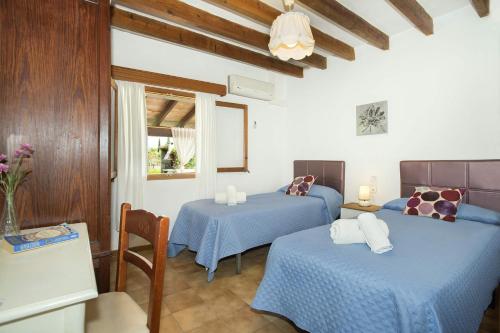 Cette chambre comprend 2 lits avec des draps bleus et une fenêtre. dans l'établissement Can Xim, à Pollença