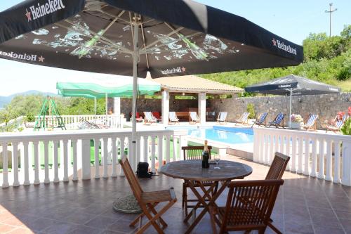 a table with chairs and an umbrella next to a pool at Apartments Vila Lazarevic in Tivat