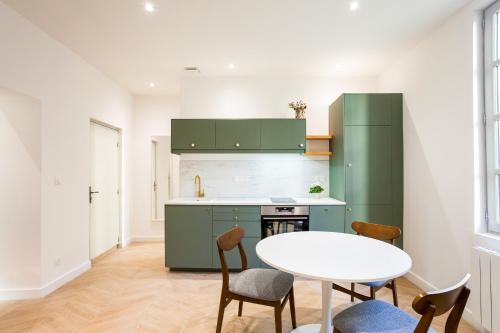 una cocina con armarios verdes, mesa y sillas en La Nuit Arlésienne - Exclusive apartments en Arlés