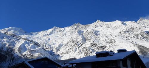 a snow covered mountain with a building in front of it at Amor Lodge in Saas-Fee