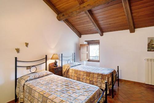 two beds in a room with wooden ceilings at La Casa della nonna in Vessalico
