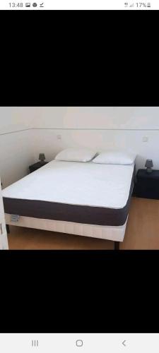 un lit avec des draps blancs et des oreillers dans une chambre dans l'établissement En pleine montagne T1 30m2 parking à coté, à Amplaing