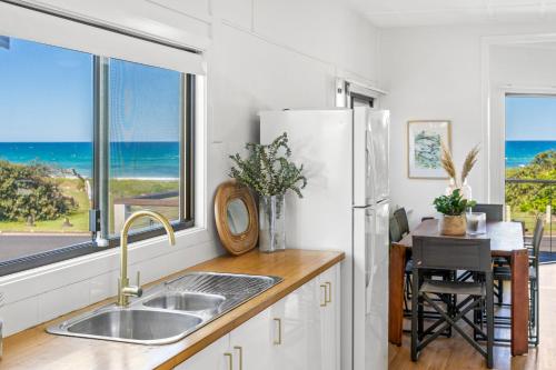 a kitchen with a refrigerator and a table with a view of the ocean at Surfside - Lennox Head in Lennox Head
