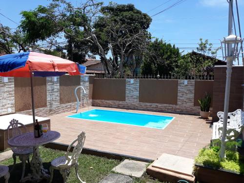 una piscina in un cortile con ombrellone di Ótima casa de praia com piscina a Rio das Ostras