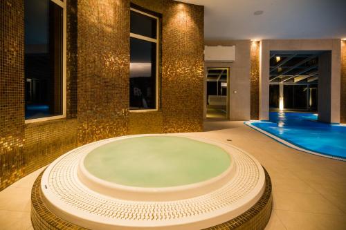 a large bath tub in a room with a swimming pool at Luxury Spa & Wellness Vila Valaška in Luhačovice