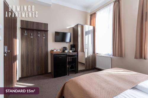 a hotel room with a bed and a desk with a television at DOMINGO Elegant Rooms KRAKÓW Old Town in Krakow