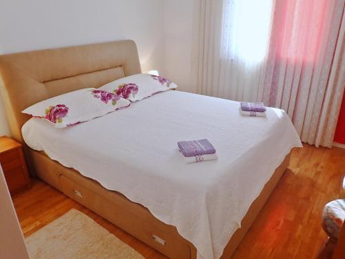 Schlafzimmer mit einem Bett mit weißer Bettwäsche und Kissen in der Unterkunft APARTMAN DANE in Rovanjska