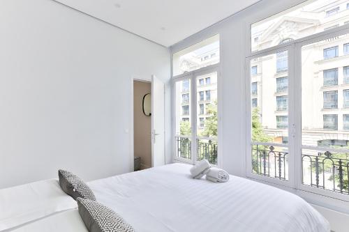 une chambre avec un lit blanc et une grande fenêtre dans l'établissement 126 - Urban Amazing 3BR Montorgueil, à Paris