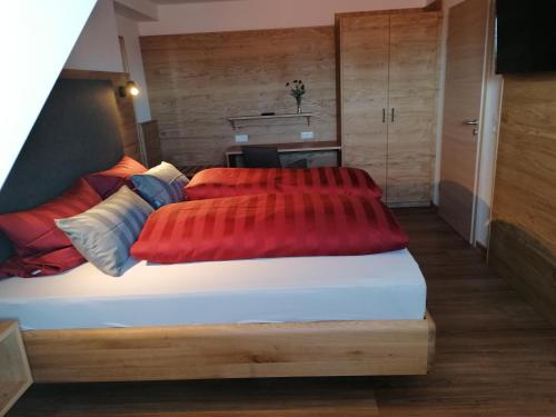 een slaapkamer met een bed met 2 rode kussens bij Pension zum Bären in Langerringen