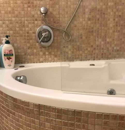 a white bath tub with a shower head on a wall at Risan Chill in Eilat