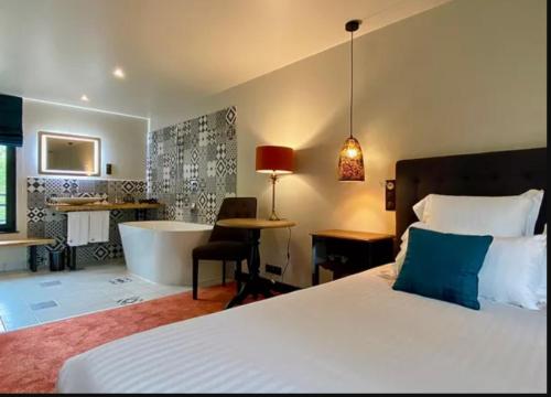 a bedroom with a bed and a bathroom with a tub at Le Moulin Fouret in Saint-Aubin-le-Vertueux