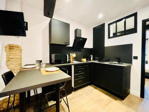 a kitchen with black cabinets and a table with chairs at L'Atelier des bords de l'Eure in Chartres