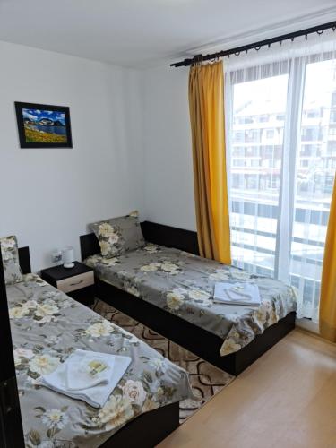 two twin beds in a room with a window at EFO Apartment in Bansko