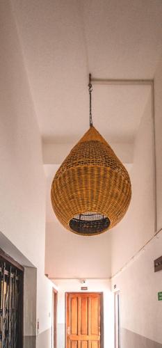 a large wicker light fixture hanging from a ceiling at Amber Rooms in Porvorim
