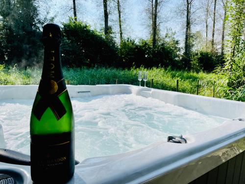 a bottle of champagne sitting in a bath tub at VILLA CALMA Rust Ruimte Luxe inclusief private jacuzzi in Zeewolde