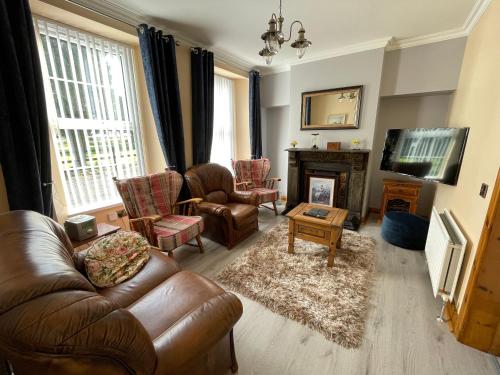 a living room with leather furniture and a fireplace at Rose Cottage in Cullybackey