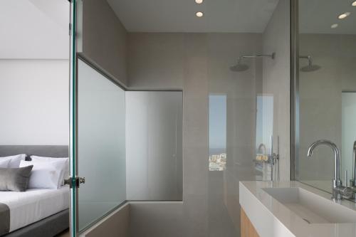 a bathroom with a shower and a bed and a sink at Ode Iconic Residence, forever in blue, By ThinkVilla in Balíon