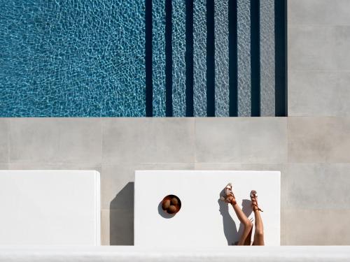 a woman laying on a bench next to a swimming pool at Ode Iconic Residence, forever in blue, By ThinkVilla in Balíon
