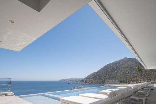 a view of the ocean from a pool with white lounge chairs at Ode Iconic Residence, forever in blue, By ThinkVilla in Balíon