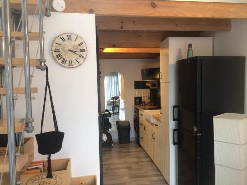a kitchen with a refrigerator and a clock on the wall at Loft Zen Climatisé in Soustons