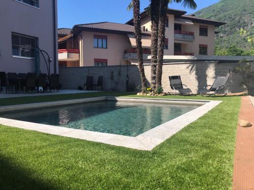a swimming pool in a yard next to a house at Miranda, Modern Duplex, Garden, Swimming Pool, Parking in Losone