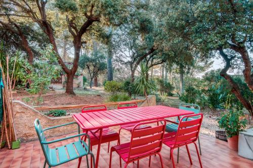 une table et des chaises rouges sur un patio arboré dans l'établissement Maison de la Grande Bastide - Welkeys, à Sanary-sur-Mer