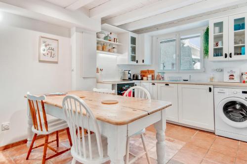- une cuisine blanche avec une table et des chaises en bois dans l'établissement Maison de la Grande Bastide - Welkeys, à Sanary-sur-Mer