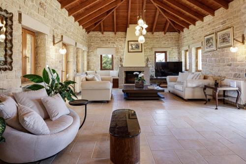 a living room with white furniture and a stone wall at Villa Lygia in Petres