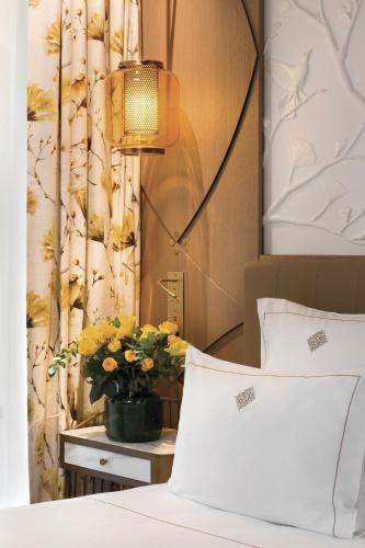 a bedroom with a bed and a flower pot on a table at La Demeure Montaigne in Paris