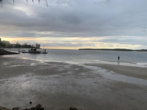 a person standing on a beach near the water at Golden Beach Motor Inn, Caloundra in Caloundra