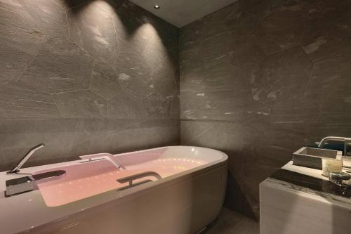 a bathroom with a pink bath tub and a sink at La Demeure Montaigne in Paris