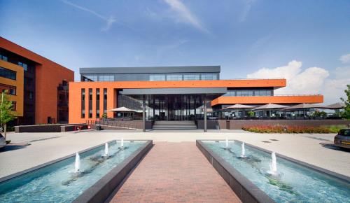 a large building with a pool in front of it at Van Der Valk Hotel Almere in Almere