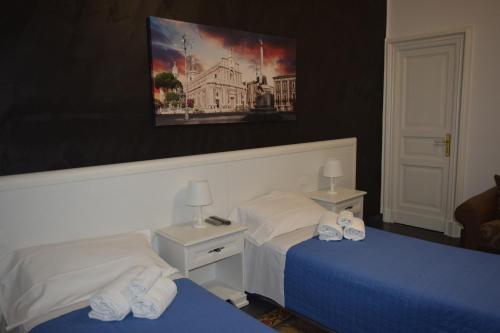B&B I Puritani في كاتانيا: غرفة فندقية بسريرين ولوحة على الحائط