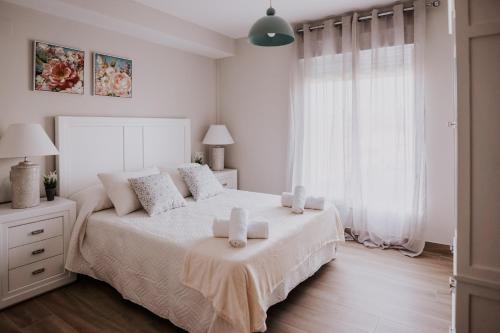 a white bedroom with a bed with two candles on it at San Rafael 4- Parking gratuito in Córdoba