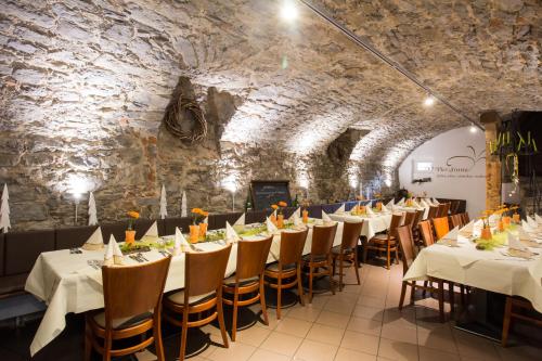 Jäger's Landhaus Rössle في Niedernhall: غرفة طعام بها طاولات وكراسي وجدار حجري