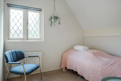 a bedroom with a bed and a chair and a window at Beautiful English Villa with hottub in Zuidwolde