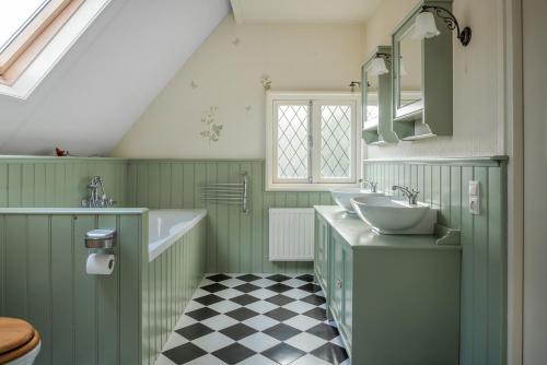 a bathroom with two sinks and a checkered floor at Beautiful English Villa with hottub in Zuidwolde