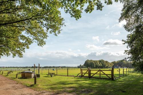 a park with a fence and picnic tables and a field at Beautiful English Villa with hottub in Zuidwolde