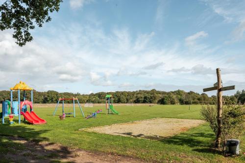 a park with playground equipment and a wooden cross at Beautiful English Villa with hottub in Zuidwolde