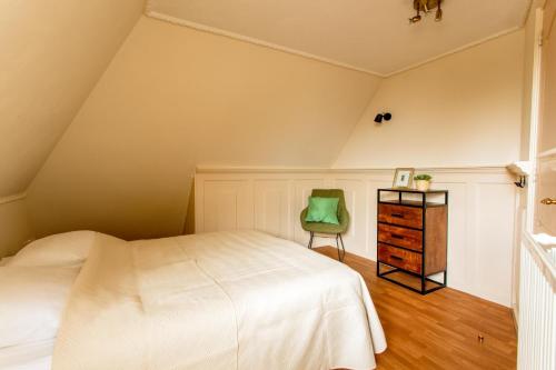 a bedroom with a white bed and a green chair at Beautiful American style villa with heated Pool and Jacuzzi in Heerhugowaard