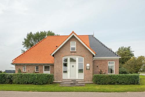 a brick house with an orange roof at Large fully renovated farmhouse with indoor Swim spa and Sauna in Lemmer