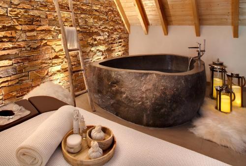 a bath tub with towels and candles on a table at LA CHENEAUDIÈRE - Hôtel Spa - Relais & Châteaux - Restaurant étoilé in Colroy-la-Roche