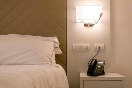 a bed with a phone and a lamp next to it at Hotel Moresco in Santa Teresa Gallura