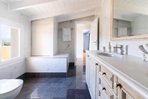 a white bathroom with a toilet and a sink at Coastline maisonette near Athens Airport and Rafina Port in Artemida